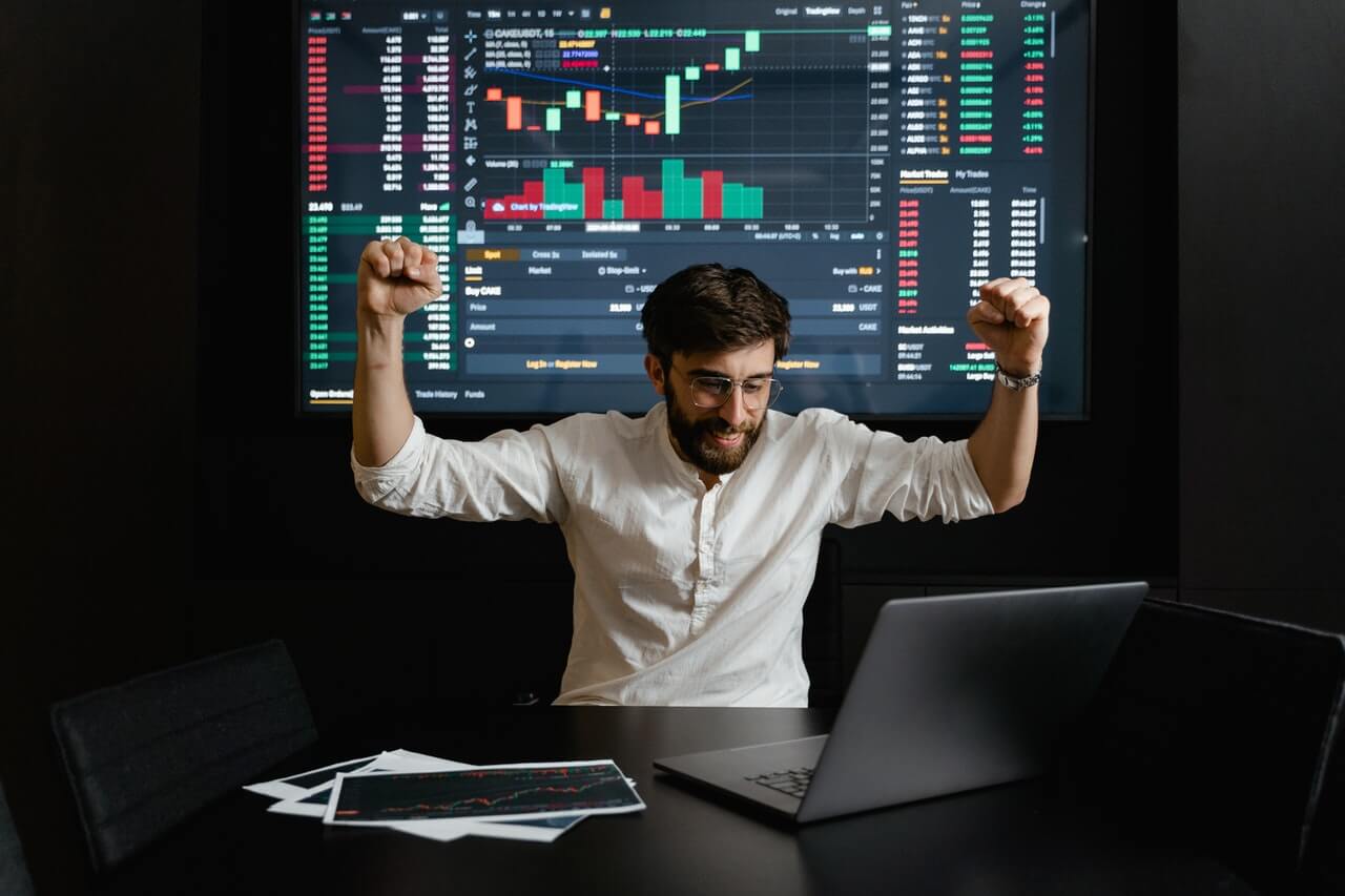 Trader celebrating in front of market screens